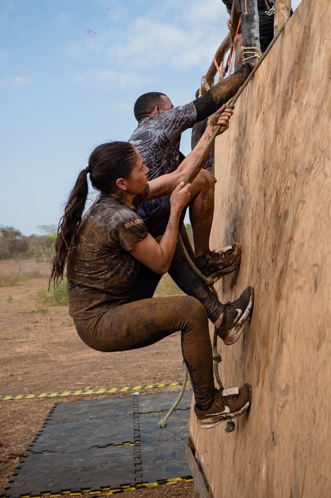 Atleta escalando muro coberto de lama na Extreme Race